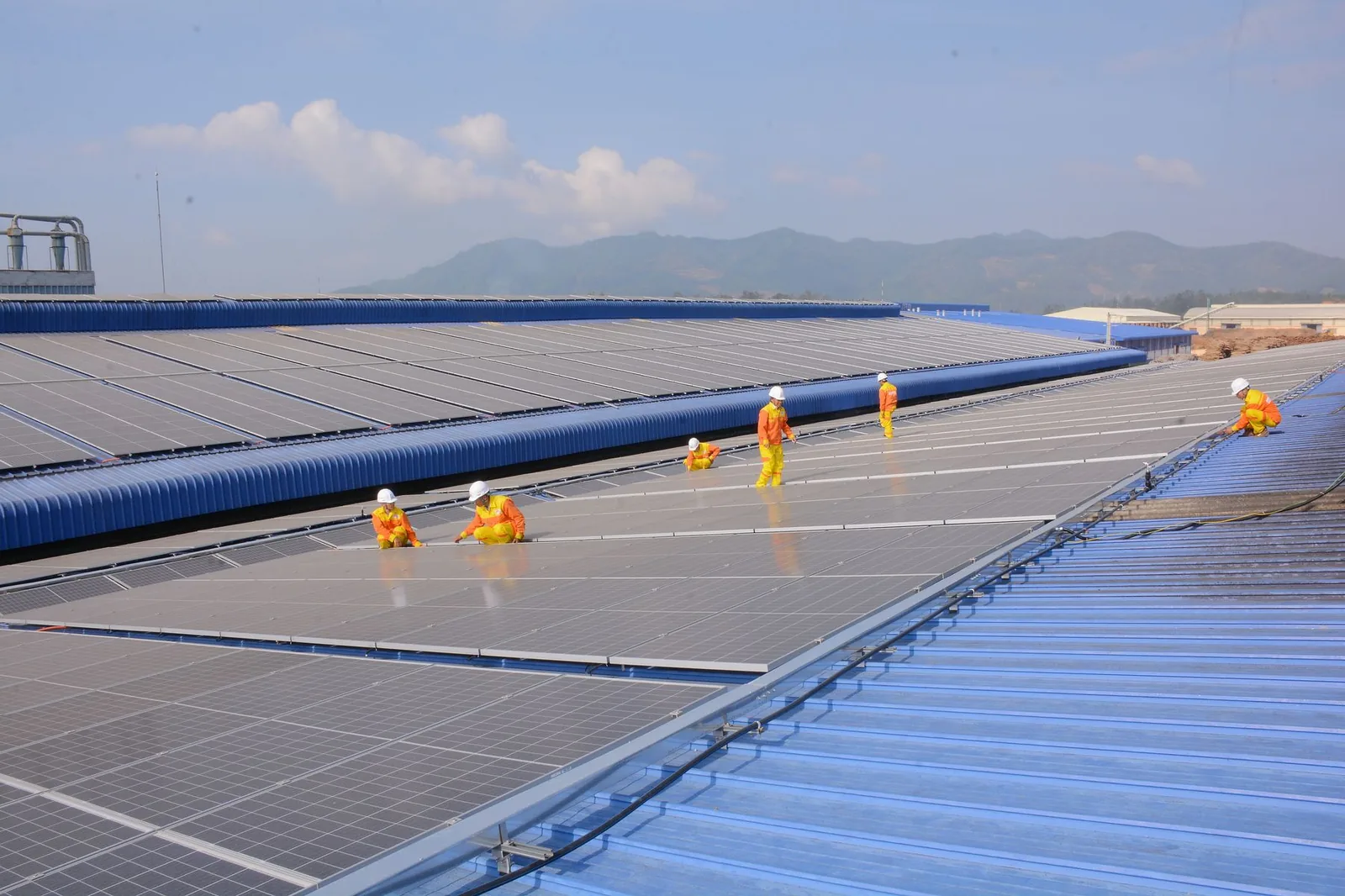 Technicians in hi-vis uniforms on a large rooftop solar array